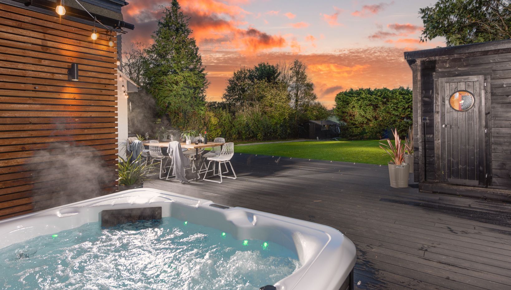 A garden with a hot tub at sunset
